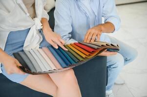 Focus on samples of colored fabrics for upholstered furniture. Overhead view of couple choosing color and fabric texture for upholstery sofa in the home. Interior design concept. photo