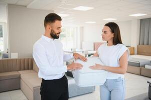 A young seller in a furniture store showing samples of mattresses in a bed photo