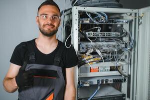 A technician works with server equipment in a data center. A man commutes wires in a server room photo
