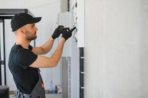 Male electrician working in a switchboard with fuses photo
