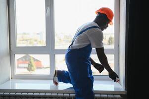 Worker installing plastic window indoors photo