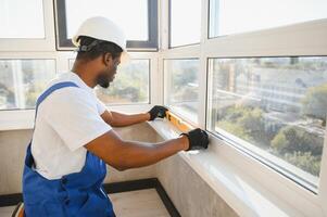 Worker in installing white plastic upvc window on house photo