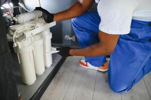 Plumber installs or change water filter. Replacement aqua filter. Repairman installing water filter cartridges in a kitchen photo