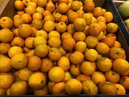 Tangerines in a box on the counter. Tangerines being sold in a store photo
