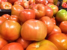 A stack of tomatoes in a market or grocery store window photo