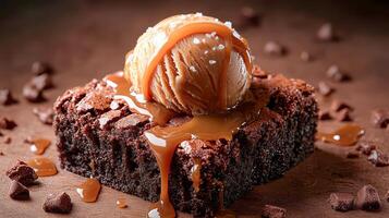 A melting ball of ice cream with salted caramel on a chocolate brownie photo