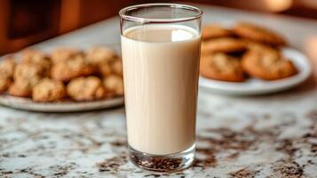 Tall glass of milk on a marble countertop with a plate of cookies photo