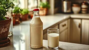 A milk bottle with a lid sits on the kitchen countertop next to a glass of milk photo