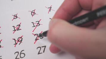 A hand marking completed dates on a calendar, showcasing impressive time management and organization skills photo