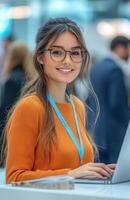 A woman in glasses is smiling while using a laptop photo