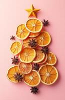 Christmas tree made of oranges and spices on pink background photo