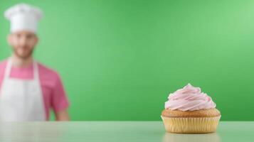 Pink Frosted Cupcake on Green Background with Blurred Chef in Apron Rear View Bokeh Effect for Bakery Advertising and Culinary Arts photo