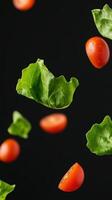 Fresh Green Lettuce and Cherry Tomatoes in Super Slow Motion Against Black Background with Probe Lens Effect photo