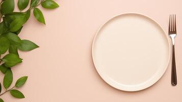 Empty beige plate with a fork and green leaves on a pastel peach background. Minimalistic flat lay composition with copy space. Dining and food concept. Design for banner, poster, or menu. photo