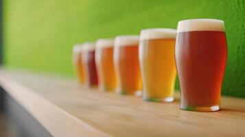 Row of craft beer glasses with varying colors on a wooden bar. Focus on foreground glass with green background. Concept of beer tasting and brewing. photo