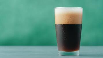 Refreshing Dark Beer with Bubbles in a Tall Glass Against a Green Backdrop Perfect for Celebrating Oktoberfest or Enjoying Craft Brew Tastings photo