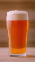 Golden Beer Pouring Into Pint Glass in Super Slow Motion with Bubbles and Foam on Top Against Wooden Background photo