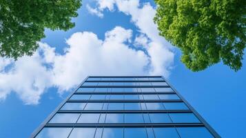 Modern Glass Building Against Blue Sky With Green Trees, Symbolizing Sustainable Architecture And Environmental Responsibility In Urban Design, Aligning With ESG Principles And Innovation photo