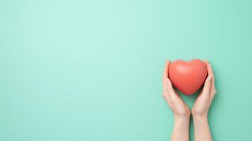 Hands gently holding a red heart-shaped object on a turquoise background. Minimalist concept of love, care, and support for design and print photo