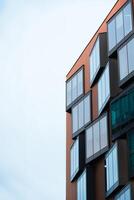 nuevo edificio arquitectura hecho de azul vaso y naranja ladrillo situado en azul cielo fondo, bajo ángulo arquitectónico exterior ver de moderno, Copiar espacio para texto foto