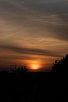 A stunning sunset with the large, radiant sun halfway below the horizon, casting a warm golden glow across the sky and railway. and the sky is adorned with subtle cloud photo