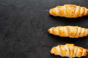 Delicious crispy three croissants on a black background. A low-key shot of food. photo