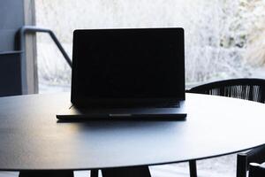 laptop on a round table with an outdoor background. Mockup design, for business, remote work, or modern workspace themes. photo