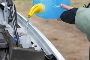 Filling a windshield washer tank with an antifreeze photo