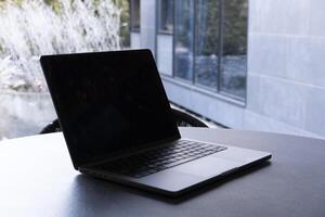laptop on a round table with an outdoor background. Mockup design, for business, remote work, or modern workspace themes. photo