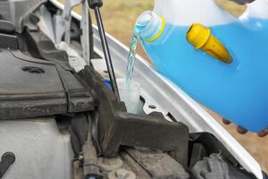 Close up of Filling a windshield washer tank with an antifreeze in winter cold weather. photo
