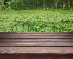 Empty brown wooden table made of old gray pine boards on the background of a lawn with green juicy grass photo