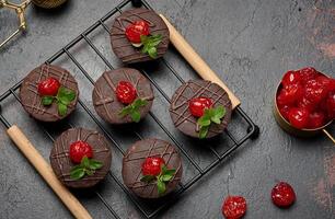 Deliciously rich chocolate brownies garnished with vibrant cherries and mint leaves, resting on a black wire rack. photo