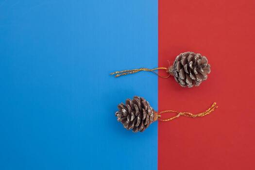 Brown pine cones with golden string loops on a vibrant blue and red background photo