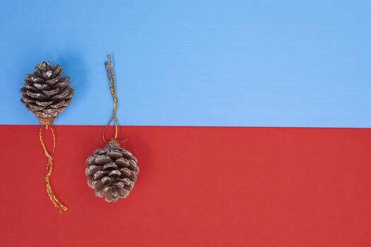 Brown pine cones with golden string loops on a vibrant blue and red background photo