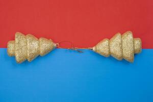 Golden glitter Christmas tree ornaments on a vibrant red and blue background photo