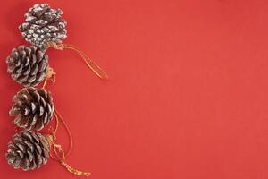 Top view of decorated pine cones lined up for Christmas decoration on a red background photo