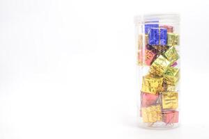 Pile of colorful gift boxes in a clear container on white background photo
