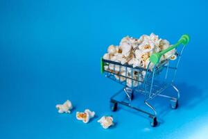 Freshly made popcorn in a shopping cart on a blue background photo