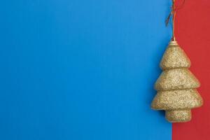 Golden Christmas tree ornament against a blue and red colorful background photo
