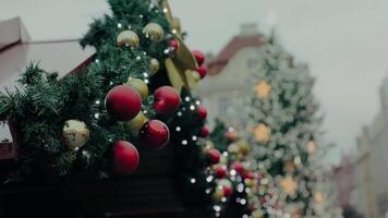 A joyful holiday scene featuring a garland with baubles and lights on a market stall, with a large decorated Christmas tree in the background. Perfect for festive, holiday, and winter-themed projects. video