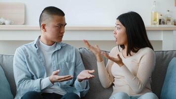 Two individuals express strong emotions while having a discussion on a couch in a bright living room. The afternoon light highlights their animated expressions and gestures. video