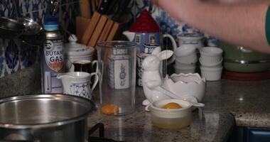 Hands break egg with knife and separate whites from yolks closeup in cooking cup. Chef prepare eggs for cooking. Kitchen space in background, camera move up. Cooking recipe step by step video