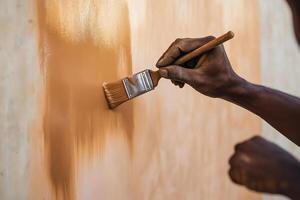 Man painting peach-fuzz wall with mocha-mousse paint, marking the color transition photo