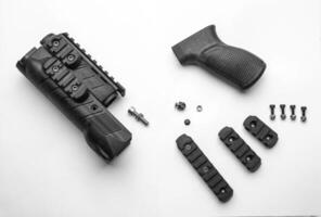 Parts of a firearm accessory, including a handguard, grip, screws, and rail sections, laid out on a white background photo