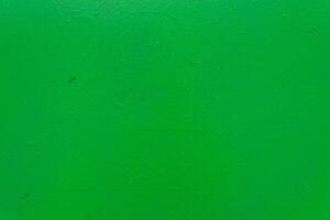 A textured green painted surface with subtle imperfections, rough texture, and small droplets. photo