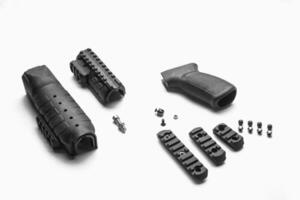 Parts of a firearm accessory, including a handguard, grip, screws, and rail sections, laid out on a white background photo