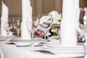Elegant table setting with folded napkins, wine glasses, and plates, perfect for a formal event or celebration, isolated on a white background. photo