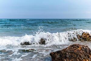 A stunning view of ocean waves crashing against rocks on a sunny day. photo