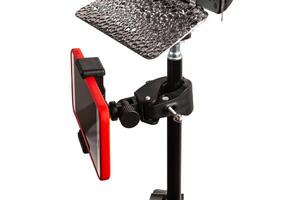 A smartphone with a red case is mounted on a black clamp attached to a stand, with a reflective surface above it. photo