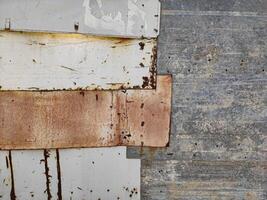 A close-up of weathered, rusty metal sheets with peeling paint and visible textures, showcasing industrial decay and the passage of time, perfect for background. photo